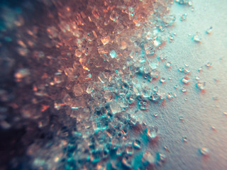 Heap of transparent white sugar crystals in mixed colour light. Macro photo