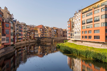 Colorful yellow and orange houses reflected in water river Onyar, in Girona, Catalonia, Spain.