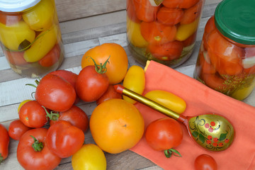 Different sort of tomatoes on wooden table with marinated tomatoes