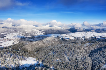 Fototapeta na wymiar Aerial view at the winter mountains. Forest from air. Winter landscape from a drone. Snowy landscape. Aerial photography