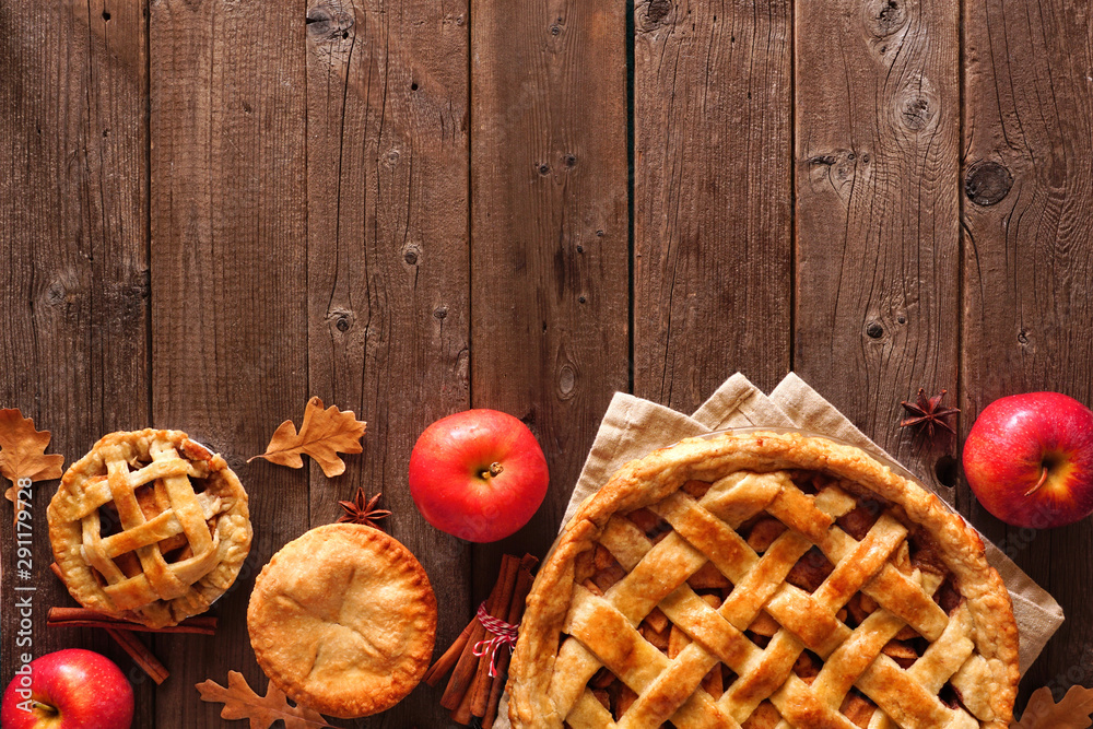 Poster Homemade autumn apple pie bottom border. Above view table scene over a rustic wood background with copy space.