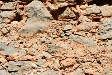 Fototapeta premium Fragment of an ancient wall illuminated by the bright sun close-up. Stone wall background.