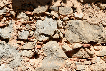 Fragment of an ancient wall illuminated by the bright sun close-up. Stone wall background.