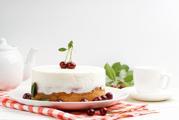Homemade cherry pie with delicate yogurt filling and cup of tea on white wooden table