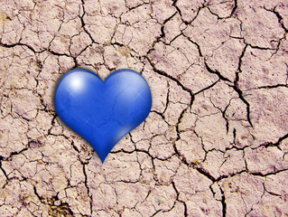 Blue heart lies on the cracked soil in the desert. Like a drop of water during a drought.
