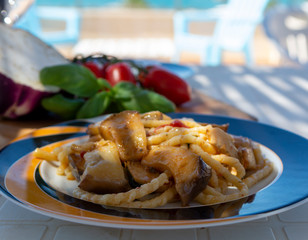 Sicilian pasta dish with traditional busiata pasta and sicilian vegetables, Viola eggplant, tomatoes served ourdoor on terrace with sea view