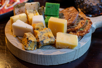 Variety of Dutch cheeses served in blocks on wooden board as dessert for dinner