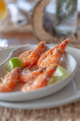 Shrimps shelled fried in garlic and oil, served on white plate garnished with lime green.