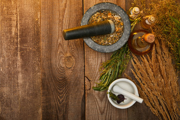 top view of mortars with pestles near fresh herbs on wooden surface with copy space