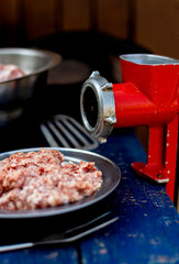 Minced meat and vintage meat grinder of red color. Men's hands make minced meat.