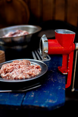 Minced meat and vintage meat grinder of red color. Men's hands make minced meat.