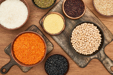 top view of bowls with whole grains and legumes on wooden cutting boards