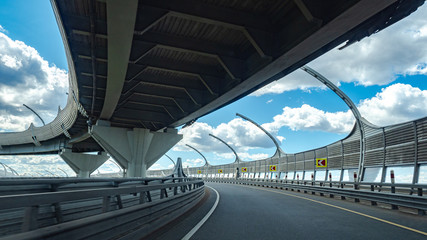 Expressway on the background of blue sky with clouds. Transport infrastructure. The highways are located on two levels. Empty Expressway. Road junction. Road safety.