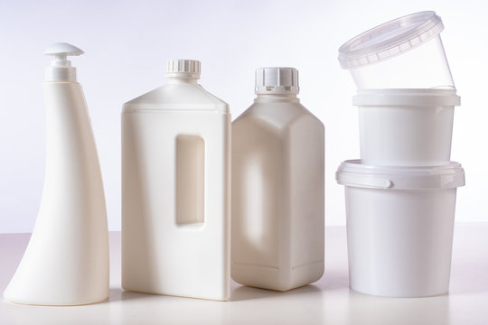 Empty plastic containers. Production of packaging for food industry and household chemicals. Nature protection.  White containers and bottles are on the table. Plastic packaging.