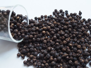 Dried black pepper seeds in a clear glass. peppercorn is a famous herb used to ingredient in Thai food. Isolated on white background