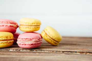 Sweet colorful French macaroon cookies dessert on brown wooden table over white wooden background