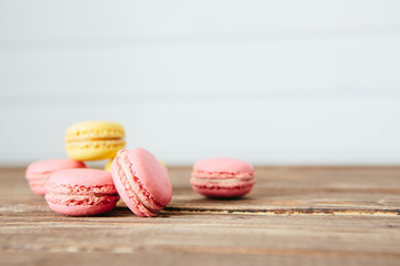Sweet colorful French macaroon cookies dessert on brown wooden table over white wooden background