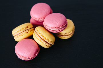 Sweet colorful French macaroon cookies dessert over black background