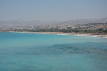 turquoise water and a beach against mountains in a haze