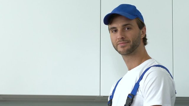 Handsome repairman workwear writing list of job done and looking to camera stuff