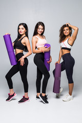 Group sport concept. Beautiful slim sporty women with yoga mat and water isolated on white background