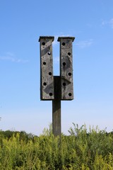 The tall wooden birdhouse in the field on a sunny day.