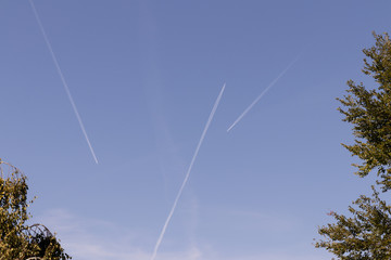 White traces in the sky from flying airplanes. Airspace Crossing