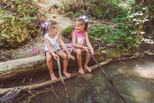 Children having fun at forest creek on summer day in nature