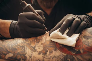 Foto op Aluminium Close up tattoo machine. Tattooing. Man creating picture on his back by a professional tattoo artist. © Zamrznuti tonovi
