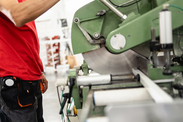 Manual worker cutting aluminum and PVC profiles. Manufacturing jobs. Selective focus. Factory for aluminum and PVC windows and doors production.