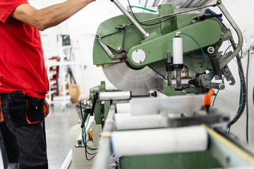 Fototapeta premium Manual worker cutting aluminum and PVC profiles. Manufacturing jobs. Selective focus. Factory for aluminum and PVC windows and doors production.