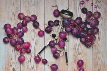 Uvas y sacacorcho sobre unas tablas 