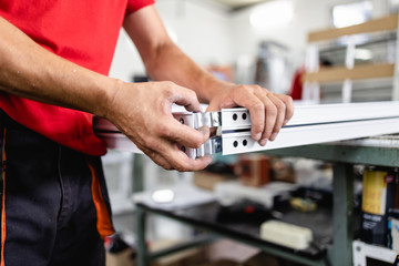 Manual worker assembling PVC doors and windows. Manufacturing jobs. Selective focus. Factory for...