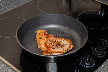 Pork chop is fried in a pan