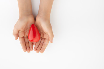 Two hands holding red blood drop on white background. Give blood. Donation concept.