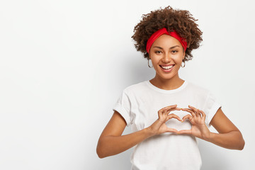 Love to you, my dear. Glad satisfied African American woman makes heart gesture, smiles pleasantly...