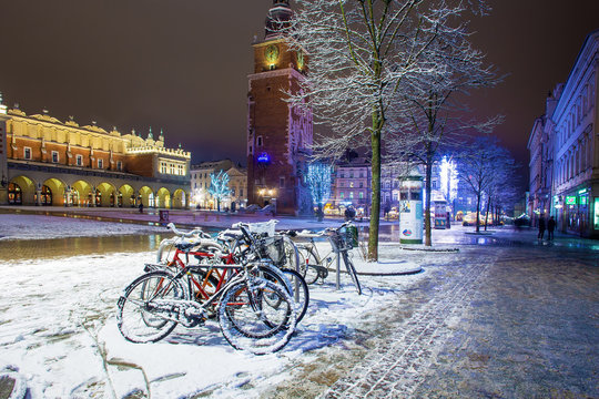Bicycles .  covered snowy town  hall tower.  Night . Krakow