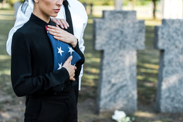 cropped view of senior man near woman with american flag on funeral