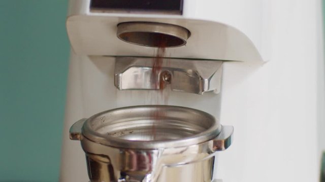 Close up video shot of coffee-grinder in process of making ground drink slow motion. Coffee-machine  preparing energetic beverage in cafe home natural light. Morning caffeine energy concept