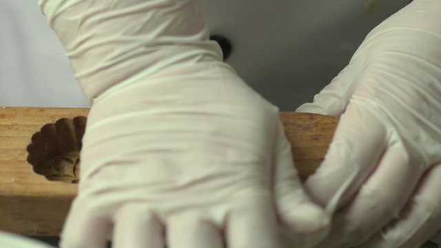 Close up of a chef hand in glove putting mooncake dough into wooden bold and tapping to release.