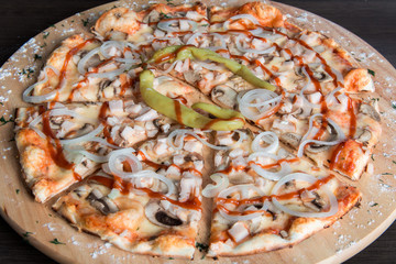 pizza with ham and mushrooms and onions on a wooden plate