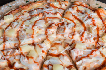 hawaiian pizza with ham and pineapples on a wooden plate