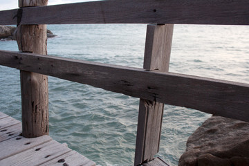 Wooden plank bridge fence detail with sea and cape stones on the background