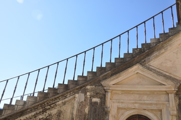 geschwungener Treppenaufgang einer Freitreppe aus Stein vor blauem Himmel 
