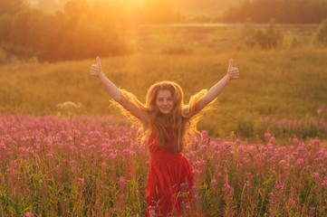 Naklejka na ściany i meble Dancing and jumping girl with thumbs up in red dress among blooming Sally field