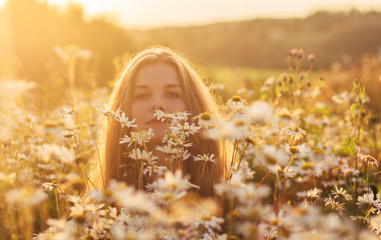 Portrait of pretty blond woman sitting in chamomile field