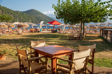 Beautiful summer calm morning empty table chairs in Antisamos beach bar, Kefalonia island, Ionian sea, Greece.
