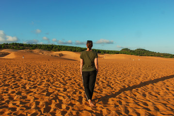 A woman from backside standing in a sand of Red Sand Dunes of Mui Ne, Vietnam 