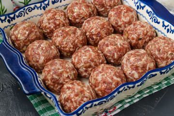 Meatballs raw with rice are cooking in ceramic form, horizontal orientation