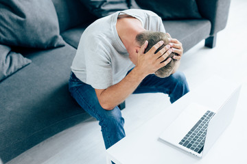 high angle view of man in t-shirt touching head in apartment